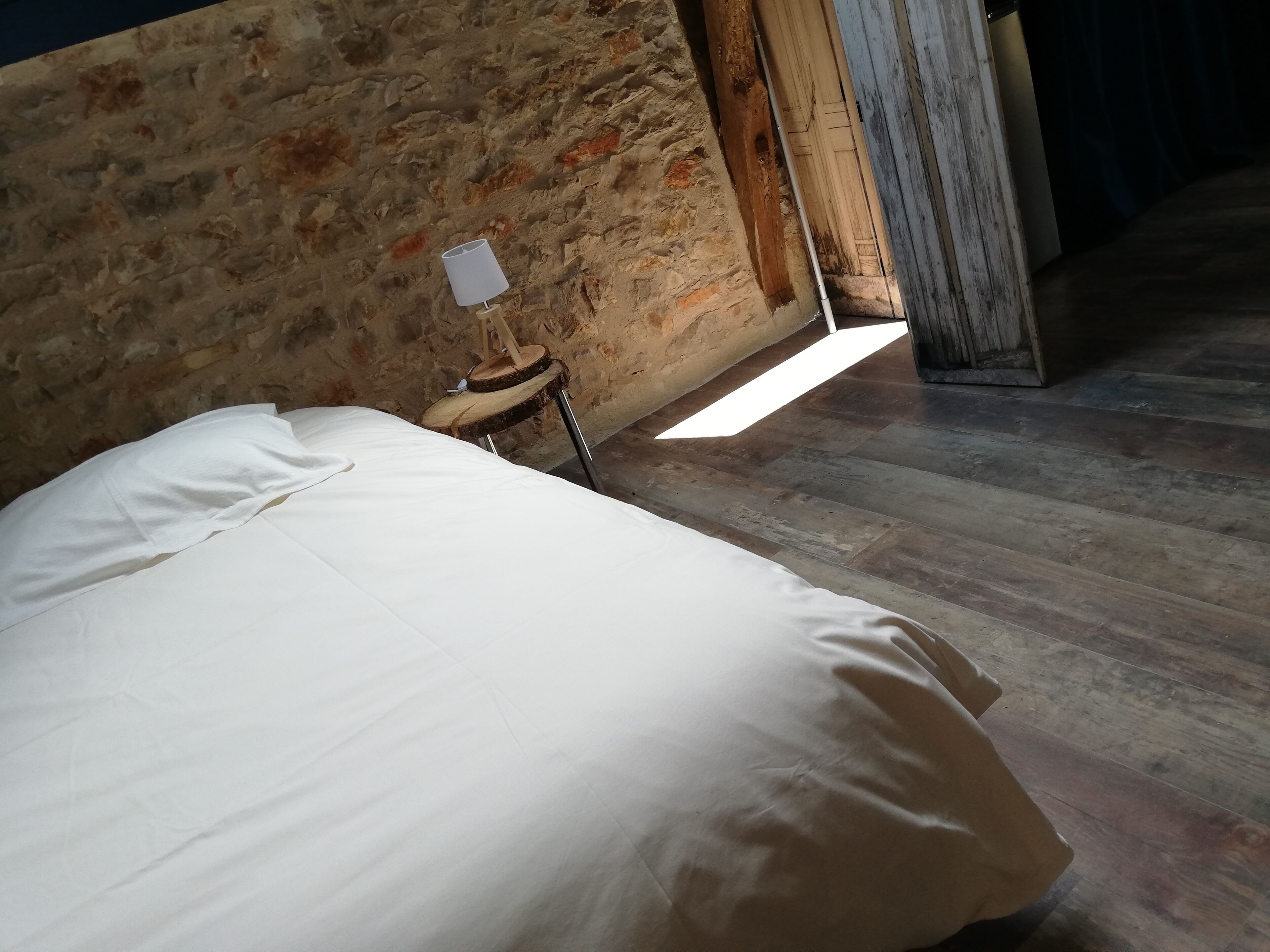 Een kamer met een bed, een houten stoel en een stenen muur.