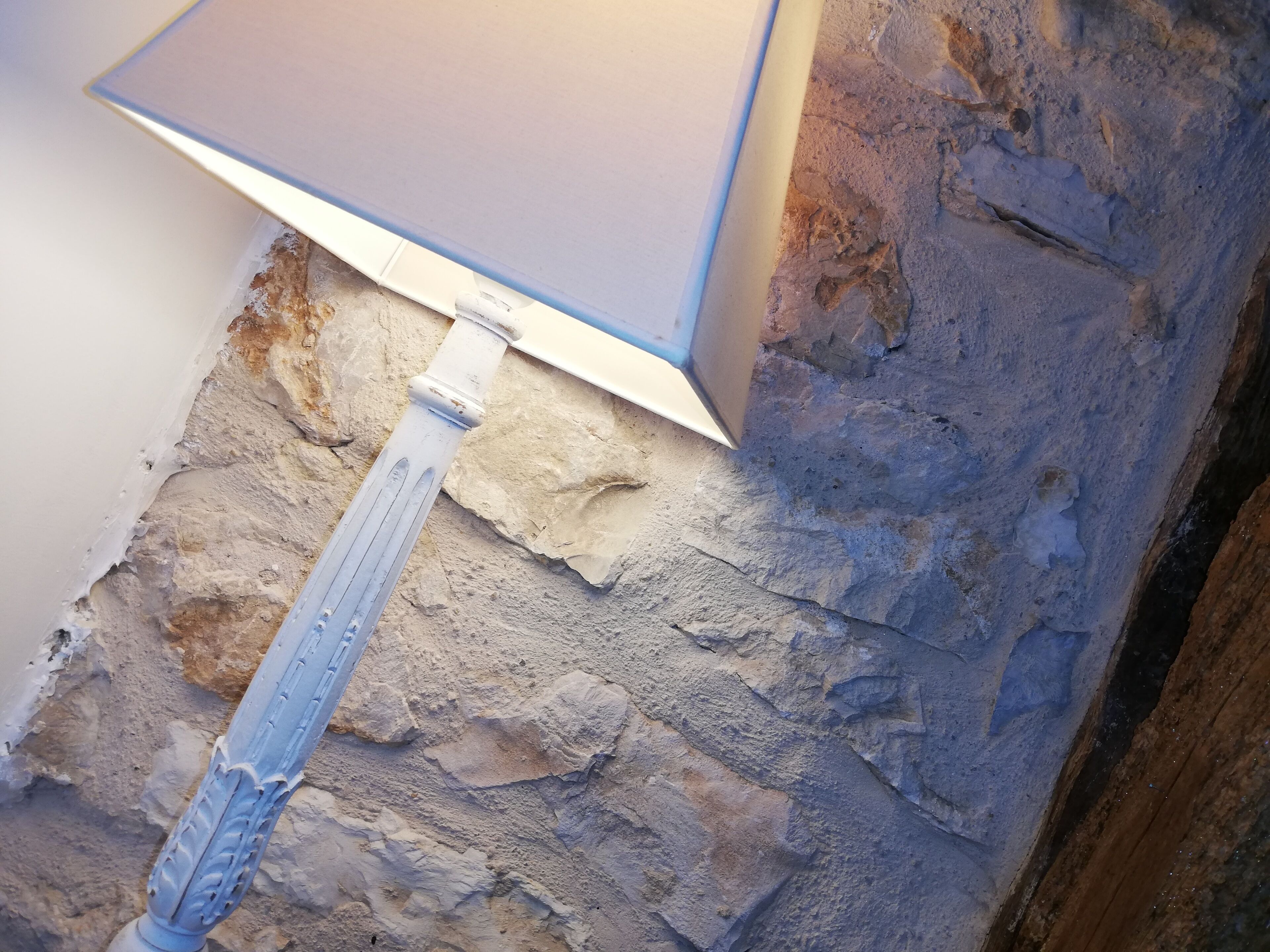 A close-up of a wall corner with a stone texture and a metal fixture.