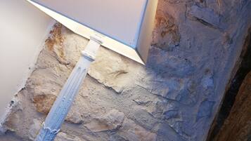 A close-up of a wall corner with a stone texture and a metal fixture.