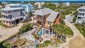 Un quartier résidentiel situé sur la côte, composé de plusieurs maisons à deux étages dotées de balcons, d’une piscine et d’un chemin d’accès à la plage.
