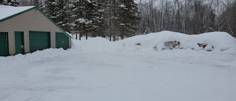 Paisaje nevado con un edificio que tiene puertas verdes y un garaje.