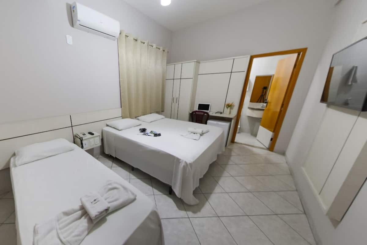 Habitación de hotel con dos camas, un escritorio, una silla, aire acondicionado y un espejo.