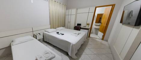 Une chambre d’hôtel avec deux lits, un bureau, une chaise, un climatiseur et un miroir.
