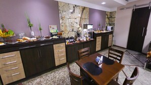 A modern kitchen with dark wooden cabinets, a marble backsplash, and a dining area with a wooden table and chairs. - NortHotel (Barra De Sao Francisco)