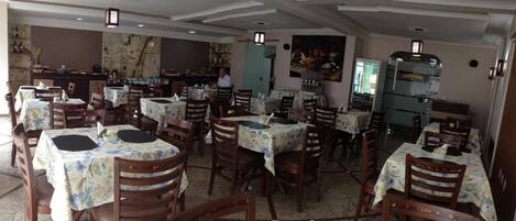 Un restaurante con varias mesas y sillas, una zona de bar y una barra.
