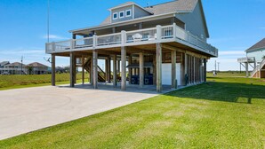 Ein Strandhaus mit überdachter Veranda, Garage und einer kleinen Sitzgelegenheit im Freien.