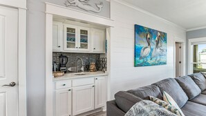 Eine Küche mit weißen Schränken, einer Steinrückwand und einem Gemälde von Pelikanen an der Wand.