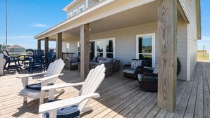 Eine überdachte Terrasse mit Adirondack-Stühlen, einer Couch und einem Esstisch.