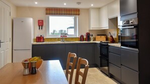 A modern kitchen with a refrigerator, stove, and sink. There is a window with a view of the outside. - The Annex at Fernyrig (Coldstream)