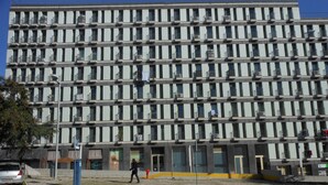 A multi-story building with numerous windows and balconies, a paved ground with a pedestrian crossing, and a parked car. - Entrecampos 6, luxury T3 apartment with garage. (Lisboa)