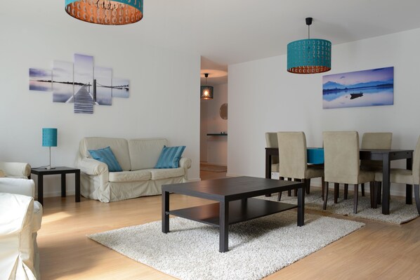 Uma sala de estar moderna com sofá, mesa de centro e área de jantar.