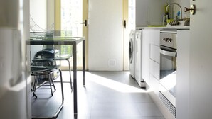 A modern kitchen with a glass dining table, a washing machine, and a built-in oven. - Entrecampos 6, luxury T3 apartment with garage. (Lisboa)