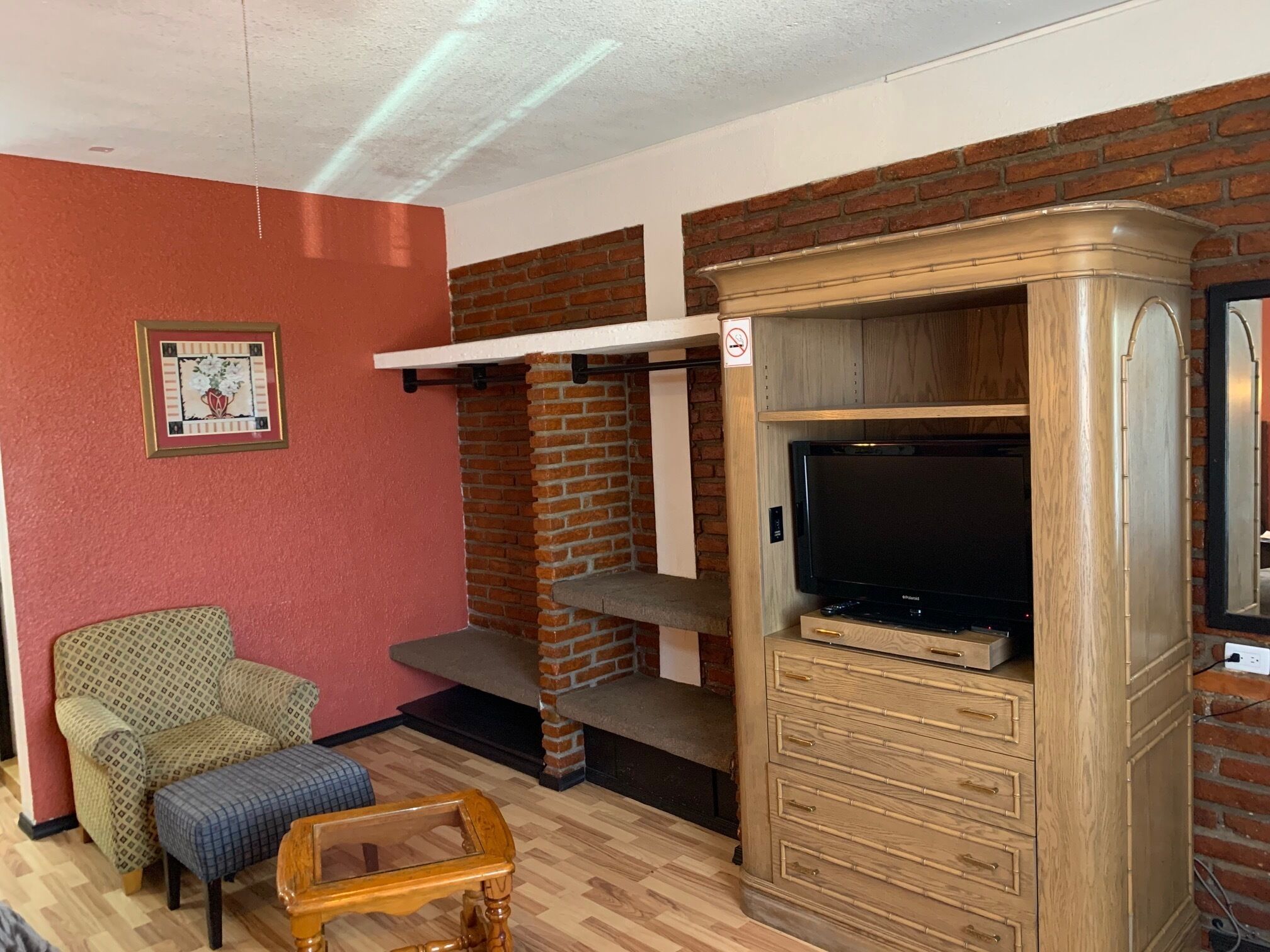 A living room with a brick wall, a television on a wooden cabinet, a sofa, and a coffee table.