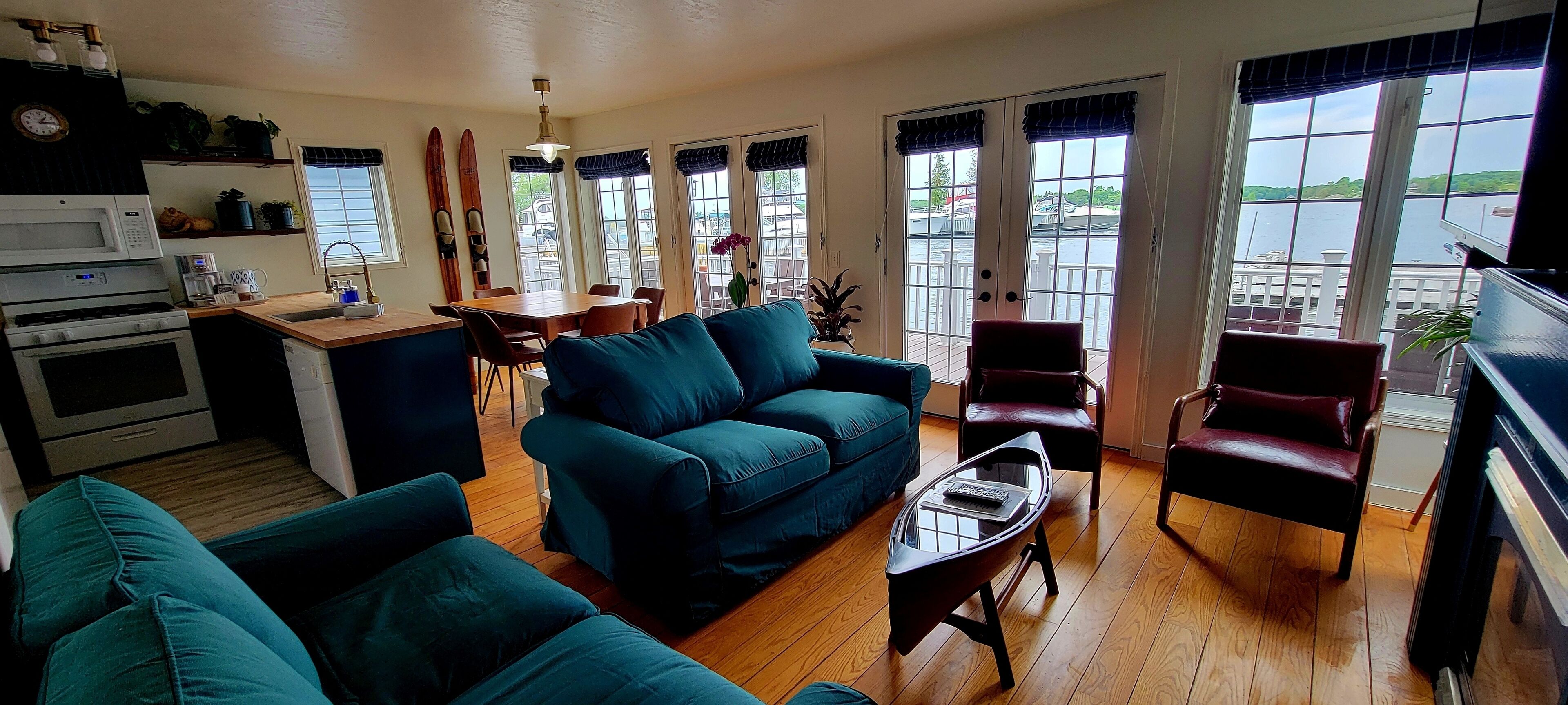 A living room with a blue sofa, a coffee table, and a dining area with a wooden table and chairs.