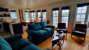 A living room with a blue sofa, a coffee table, and a dining area with a wooden table and chairs.