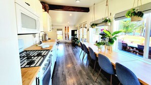 A kitchen with a wooden countertop, a stove, and a dining area with chairs and a table.