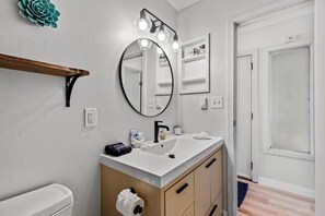 A bathroom with a white sink, a round mirror, and a wooden vanity. - ⭐️ Ski Run Steps Away, 2 Hot Tubs, Private Deck (Steamboat Springs)