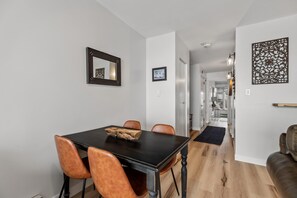 A dining area with a dark wooden table and four chairs, a mirror on the wall, and a decorative panel. - ⭐️ Ski Run Steps Away, 2 Hot Tubs, Private Deck (Steamboat Springs)