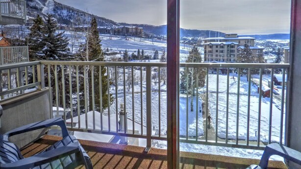 A balcony with a view of a snow-covered landscape, including a ski resort and buildings. - ⭐️ Ski Run Steps Away, 2 Hot Tubs, Private Deck (Steamboat Springs)