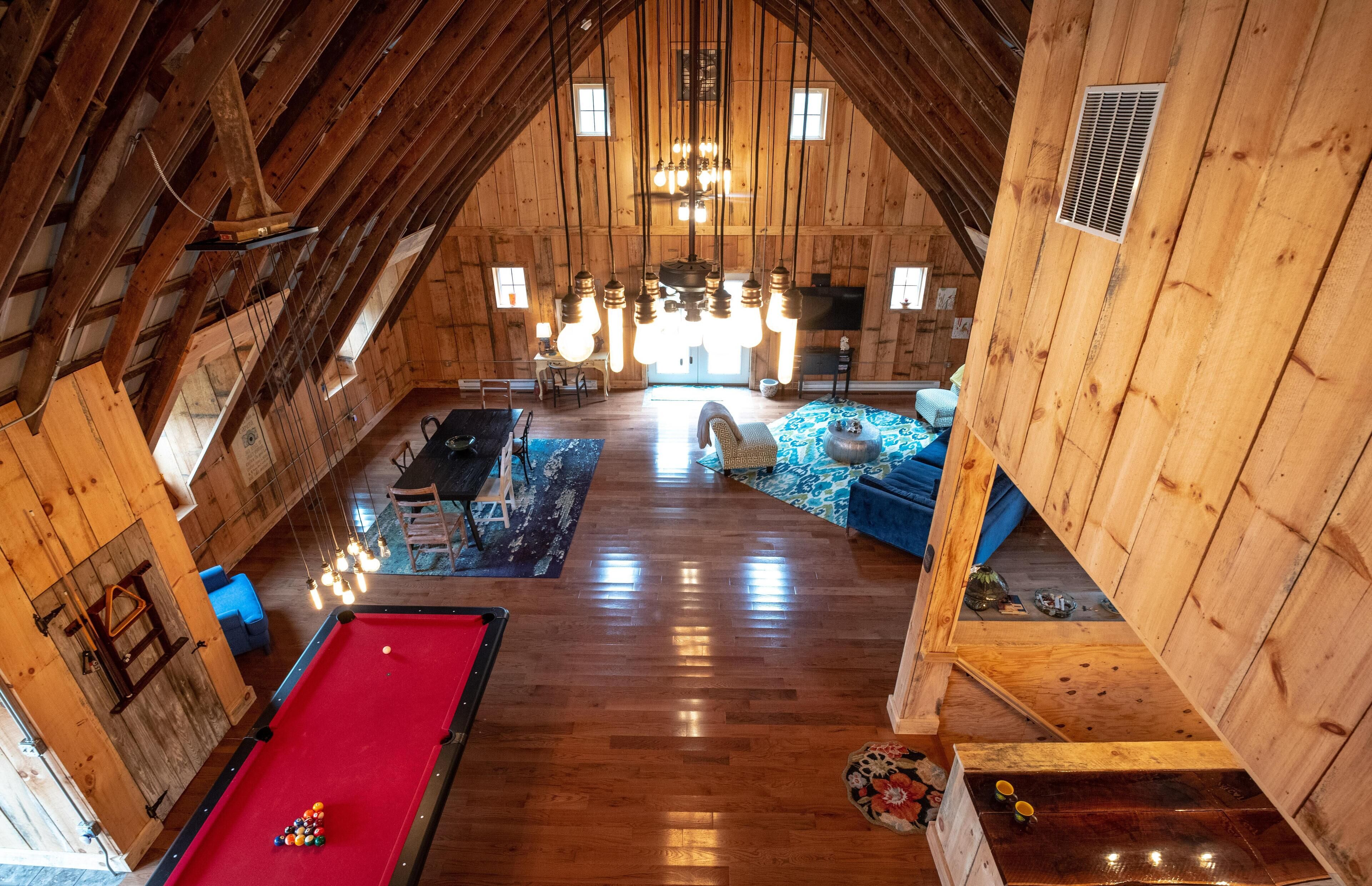 Ein geräumiges Loft mit Pooltisch, blauem Sofa und Holzboden.