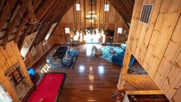 Ein geräumiges Loft mit Pooltisch, blauem Sofa und Holzboden.