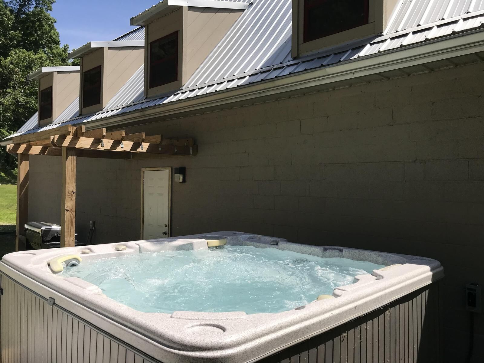 A hot tub in a covered outdoor area with a pergola structure.