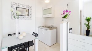 A compact kitchen with a white refrigerator, a small sink, and a dining area with a table and chairs. - Apartments A&M - Studio with Terrace and Sea View No. 2 (Mlini)