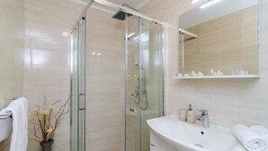 A modern bathroom with a glass-enclosed shower, a white sink, and a mirror above it.