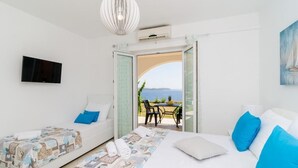A hotel room with a bed, a sofa, a TV, and a balcony with a table and chairs.