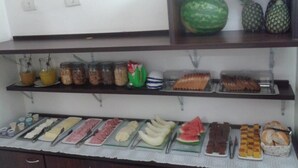 Un bufé con diversas opciones de comida, entre ellas frutas, pastelería y bebidas.