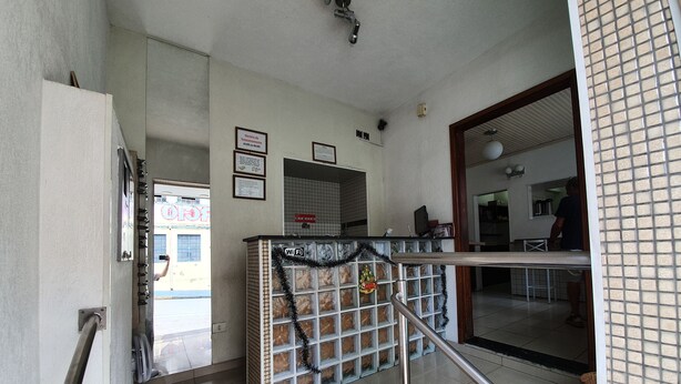 Zona de recepción de hotel con suelo de baldosas, un mostrador y una escalera.