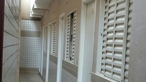 Un pasillo con paredes de baldosas y puertas, que conduce a habitaciones individuales.