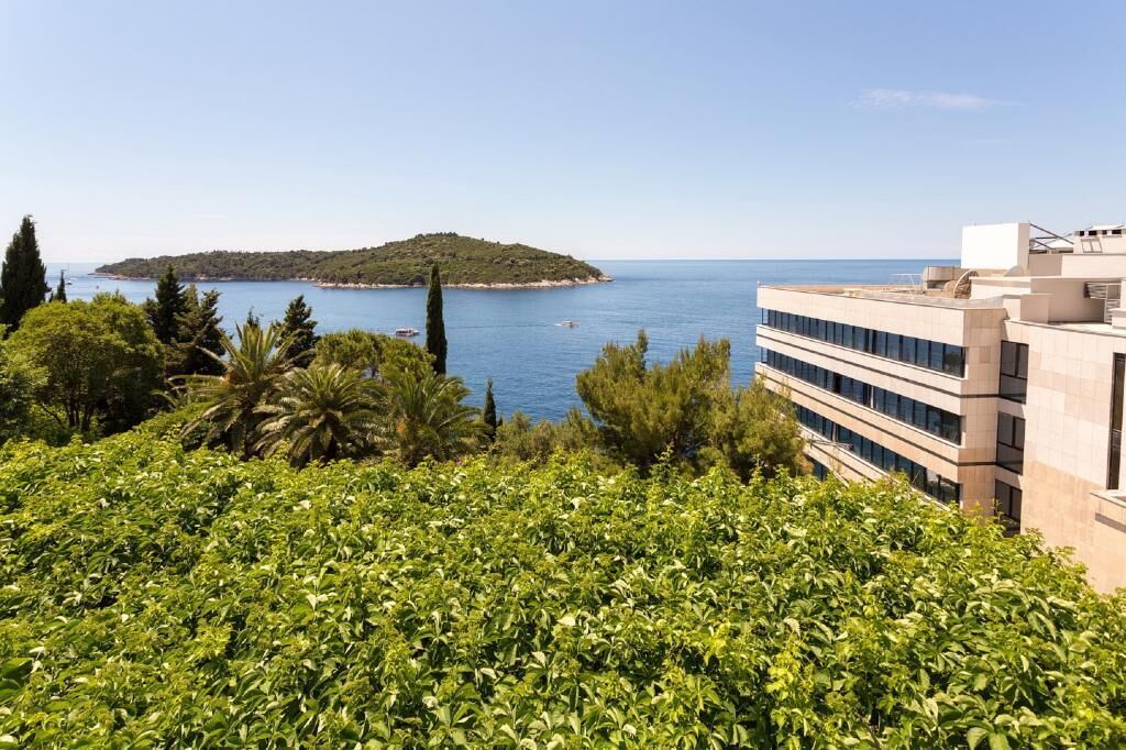 Blick auf die Küste mit einem mehrstöckigen Gebäude und freiem Blick auf das Meer und einer kleinen Insel in der Ferne.