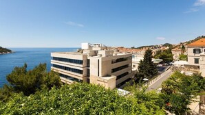 Un paisaje urbano costero con edificios modernos, cielo azul despejado y vista al mar.