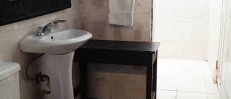 Un baño con un lavabo blanco, un espejo y una mesita de madera oscura.