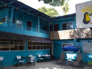 A blue building with a balcony, outdoor seating area, and a large mural.