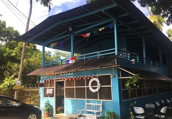 A two-story building with a blue exterior, a balcony with a railing, and a flag.