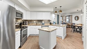 A modern kitchen with white cabinetry, stainless steel appliances, a central island, and a skylight.
