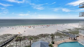 A beach view with a pool, a wooden deck, and a boardwalk.