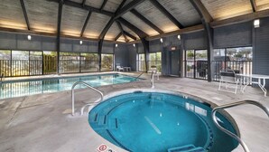 An indoor swimming pool with two separate sections, metal railings, and a covered roof structure.