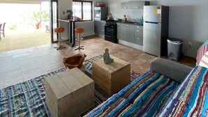 A spacious living area with a kitchen, a dining table, and a colorful rug. - Sol Patch at Jeremi #2: a seaside guest house overlooking the Caribbean. (Willemstad)