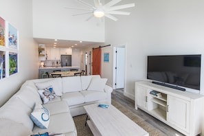 A modern living room with a white sofa, a coffee table, and a TV on a wooden stand. - Lovely GULF FRONT unit with amazing Beach Views from the balconies of LR and MB! (Santa Rosa Beach)