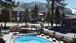 Ett poolområde med solstolar och utsikt över berg i bakgrunden.