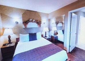 A hotel room with a large bed, two bedside tables with lamps, a mirror, and a door leading to another room. - Charming 2-bedroom townhome in Incline Village close to mountain and restaurants (incline village)