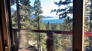 A wooden deck with a glass door leading to a view of a forest and a body of water. - Charming 2-bedroom townhome in Incline Village close to mountain and restaurants (incline village)