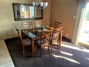 A dining area with a glass-top table, wooden chairs, a chandelier, and a large mirror on the wall. - Charming 2-bedroom townhome in Incline Village close to mountain and restaurants (incline village)
