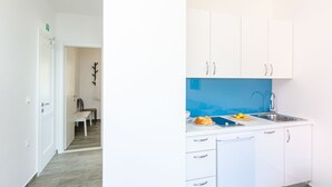 Een moderne keuken met witte kasten, een blauwe achterwand en een roestvrijstalen spoelbak.