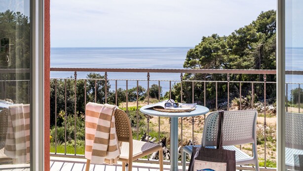 Un balcon avec une table et des chaises, donnant sur un paysage côtier.