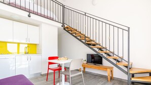 Un espace de vie compact comprenant une cuisine, un coin repas et un escalier.