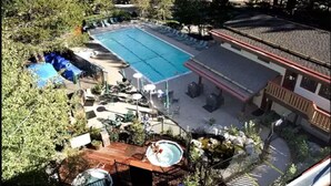 En swimmingpool med liggestole, et boblebad og en terrassedæk.